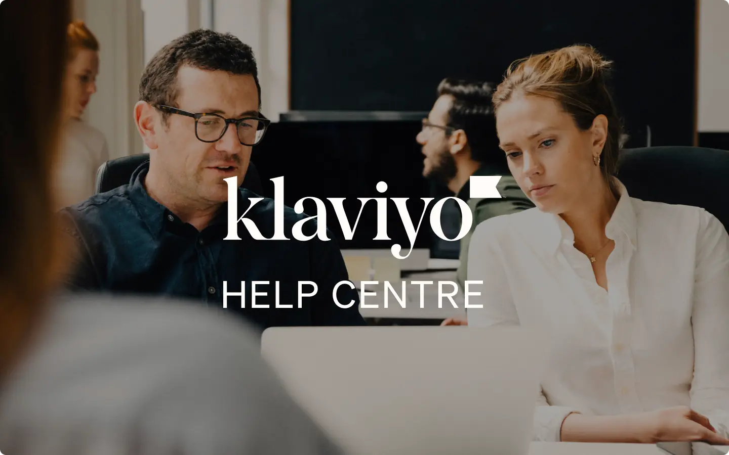 Two people working at a desk with laptops, overlaid with "Klaviyo Help Centre" text.