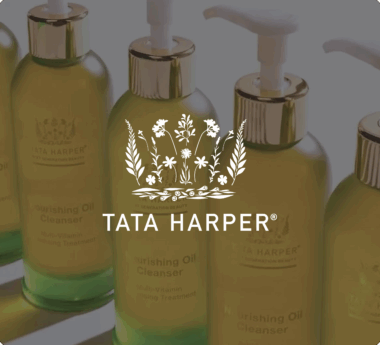 Botellas de aceite limpiador nutritivo de Tata Harper con dispensadores y un logotipo floral superpuesto