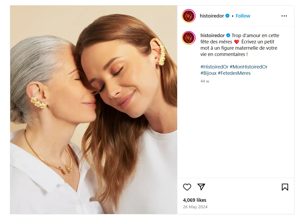 Publication Instagram d’Histoire d’Or pour la Fête des Mères 2024. Une femme âgée aux cheveux gris enlace tendrement une femme plus jeune, toutes deux souriantes et les yeux fermés. Elles portent des bijoux dorés assortis (boucles d’oreilles, colliers), symbolisant un lien affectif fort et l’intemporalité du bijou comme cadeau. Le visuel transmet chaleur, complicité et élégance.