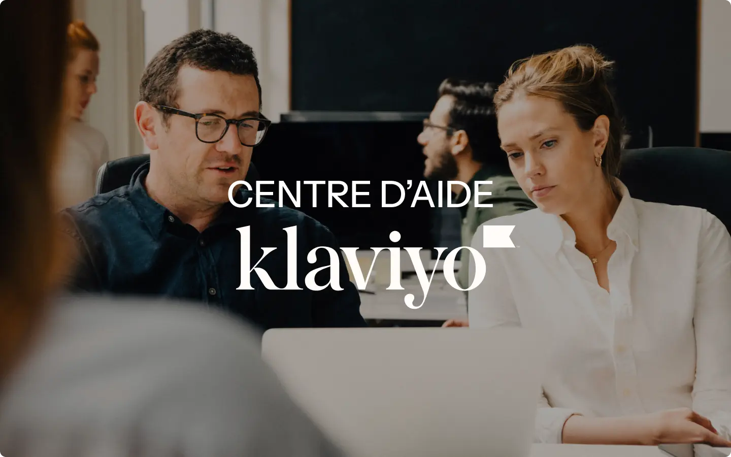 Deux personnes regardent un écran d'ordinateur avec le texte "Centre d'aide Klaviyo" superposé.