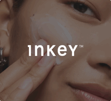 Una persona applica la crema sulla guancia con il testo &quot;Inkey&quot; sovrapposto.