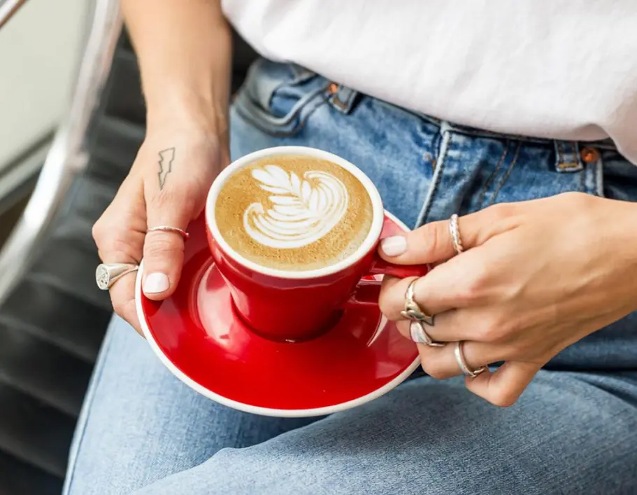 Une personne tenant une tasse de café dans ses mains.