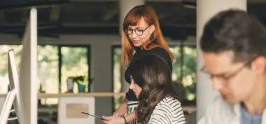 red-haired woman talking to her colleagues in an office