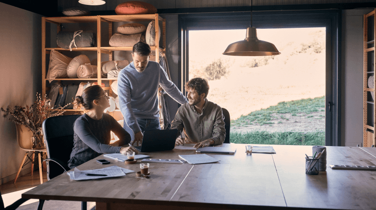 Three people working from home around a wooden table
