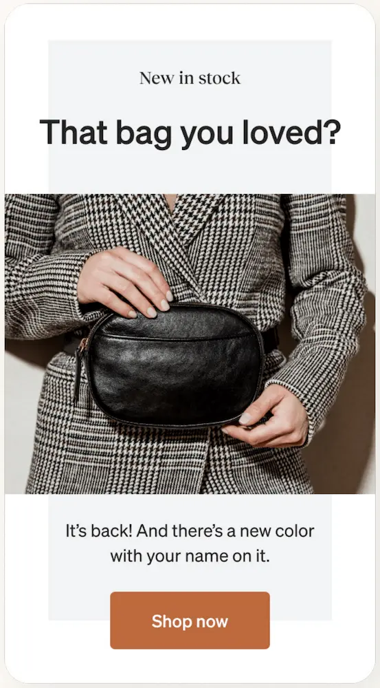 Image shows a product announcement email based on a positive customer review. The headline says, “New in stock: That bag you loved?” After a product shot of the someone in a plaid winter coat holding a black leather bag, the email continues, “It’s back! And there’s a new color with your name on it.” The CTA button at the bottom of the email is burnt orange and reads, “Shop now.”