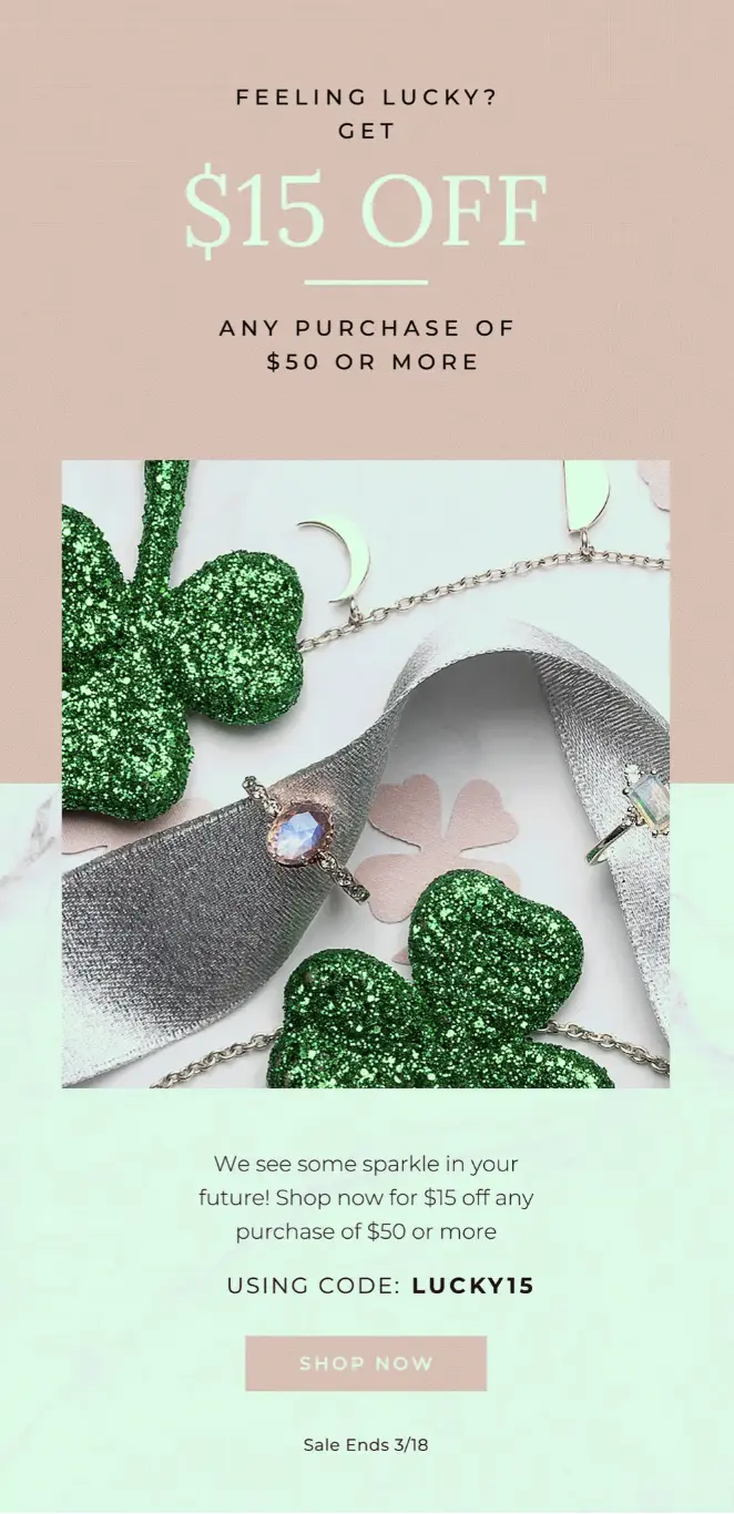 Image shows a St. Patrick’s Day email from jewelry brand Moon Magic, which reads, “Feeling lucky? Get $15 off any purchase of $50 or more” in mint font on a rose background, above a close-up product shot of two rings and a bracelet, arranged near some sparkly four-leaf clovers. The background color of the email switches from rose to mint halfway down, and the copy under the image reads, “We see some sparkle in your future! Shop now for $15 off any purchase of $50 or more using code: LUCKY15” in black. At the bottom of the email is a rose-colored CTA button that reads “SHOP NOW” in mint font, followed by a subtle deadline in black: “Sale Ends 3/18.”