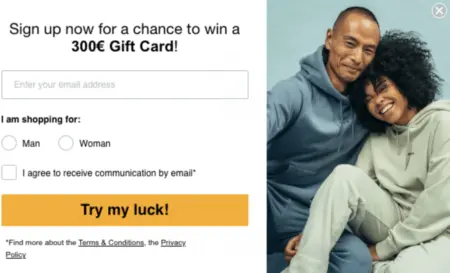 Image shows a sign-up form featuring a picture of a couple wearing blue and green jogging suits, cuddling close to each other and smiling at the camera. The header indicates that shoppers can sign up to be entered into a contest for a gift card, then asks whether they are shopping for a man or a woman. The call-to-action button says, “Try my luck!”