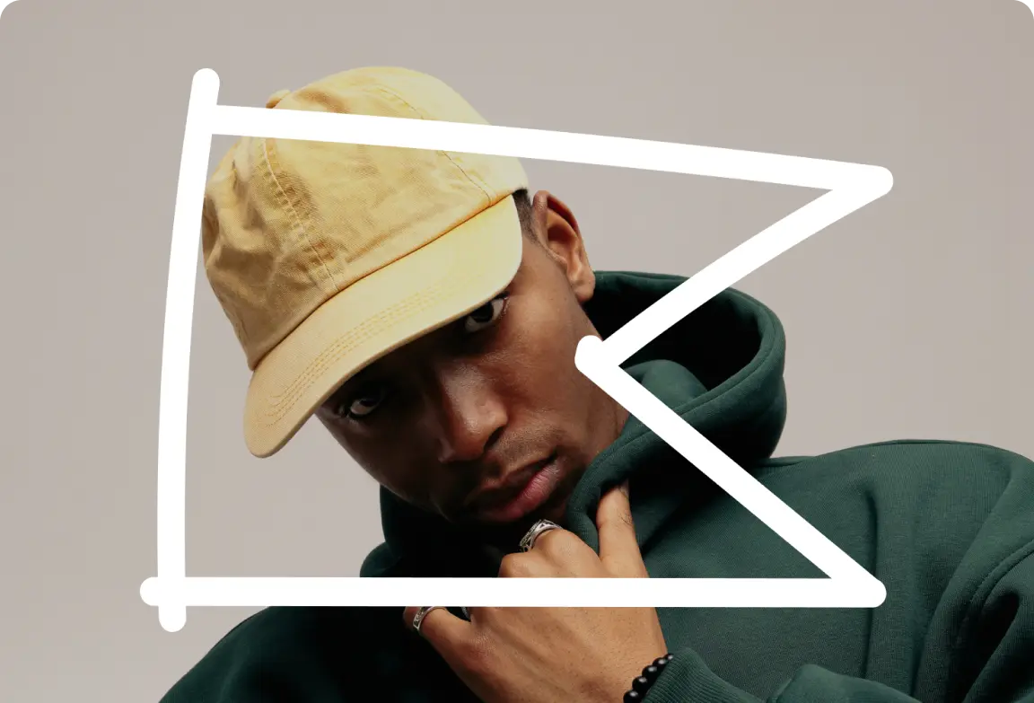 Person in a yellow cap and green hoodie, partially obscured by a white geometric shape.